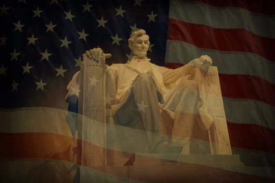 Statue of Abraham Lincoln at Lincoln Memorial with American flag in the background