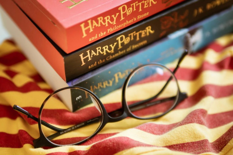 Stack of Harry Potter books next to round glasses.