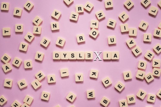 A variety of wooden letter tiles with ‘dyslexia’ spelled in the middle.