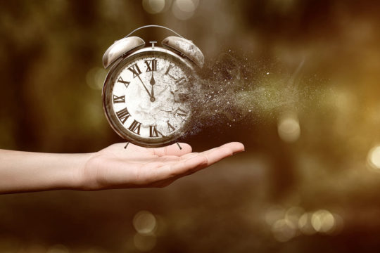 A hand holding clock that is evaporating