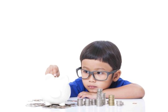 Young boy putting coins into a piggy bank