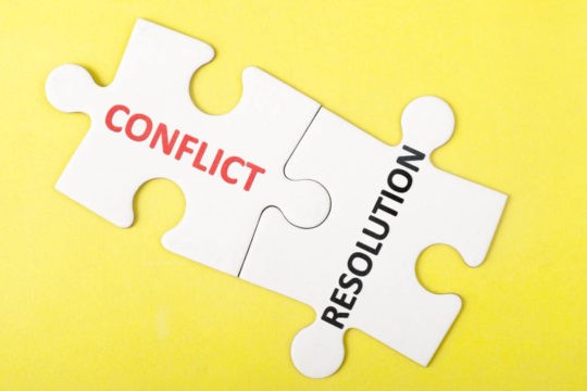 Two puzzle pieces fit together, one saying ‘conflict’, the other saying ‘resolution’.