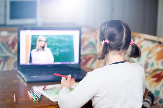 Young girl on a Zoom class video call with her teacher and classmates.