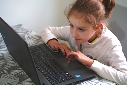 Young girl working intently on a computer during online learning.