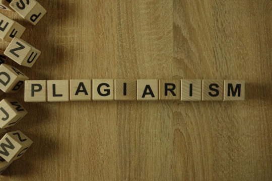 On a table ‘Plagiarism’ spelled out in wooden blocks.