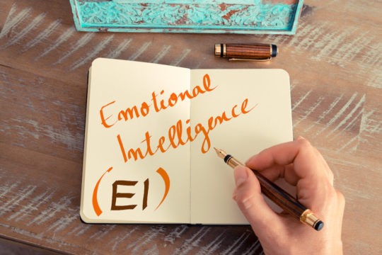 Someone writing ‘Emotional Intelligence’ in a notebook.