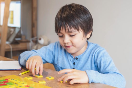 Young boy playing with tiles with letters on them.