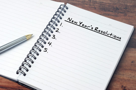 Open notebook and pen with “New Year’s Resolutions” written on the page