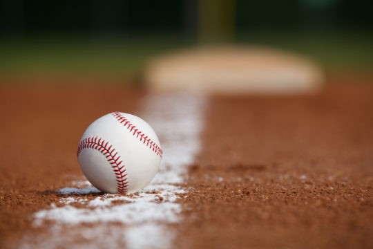 Baseball sitting in dirt on baseball field