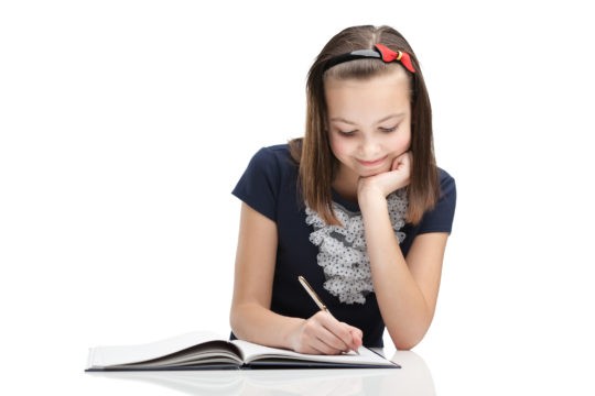 Young girl writing a story in her notebook