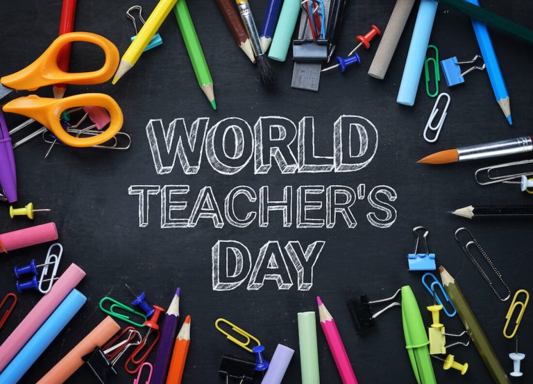 World Teachers Day is written on a chalkboard with school stationary surrounding it.