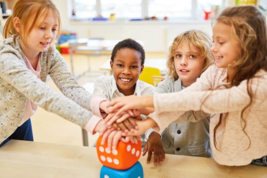 Young students stacking hands after playing a game.
