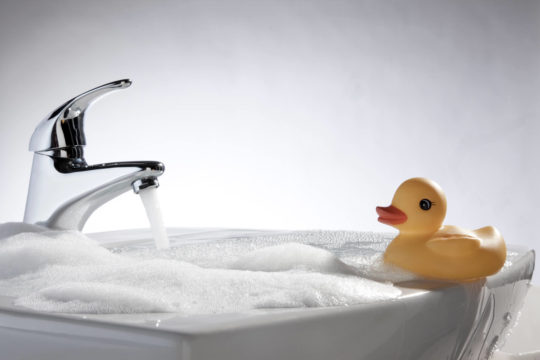 Rubber duck floating in sink filled with water