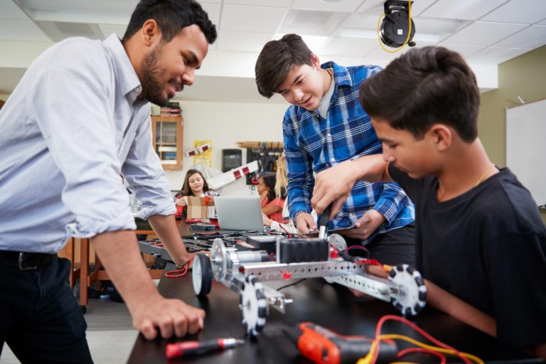 Teacher with students working on robotics project.