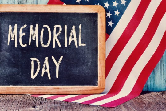 'Memorial Day' written on chalkboard next to American flag